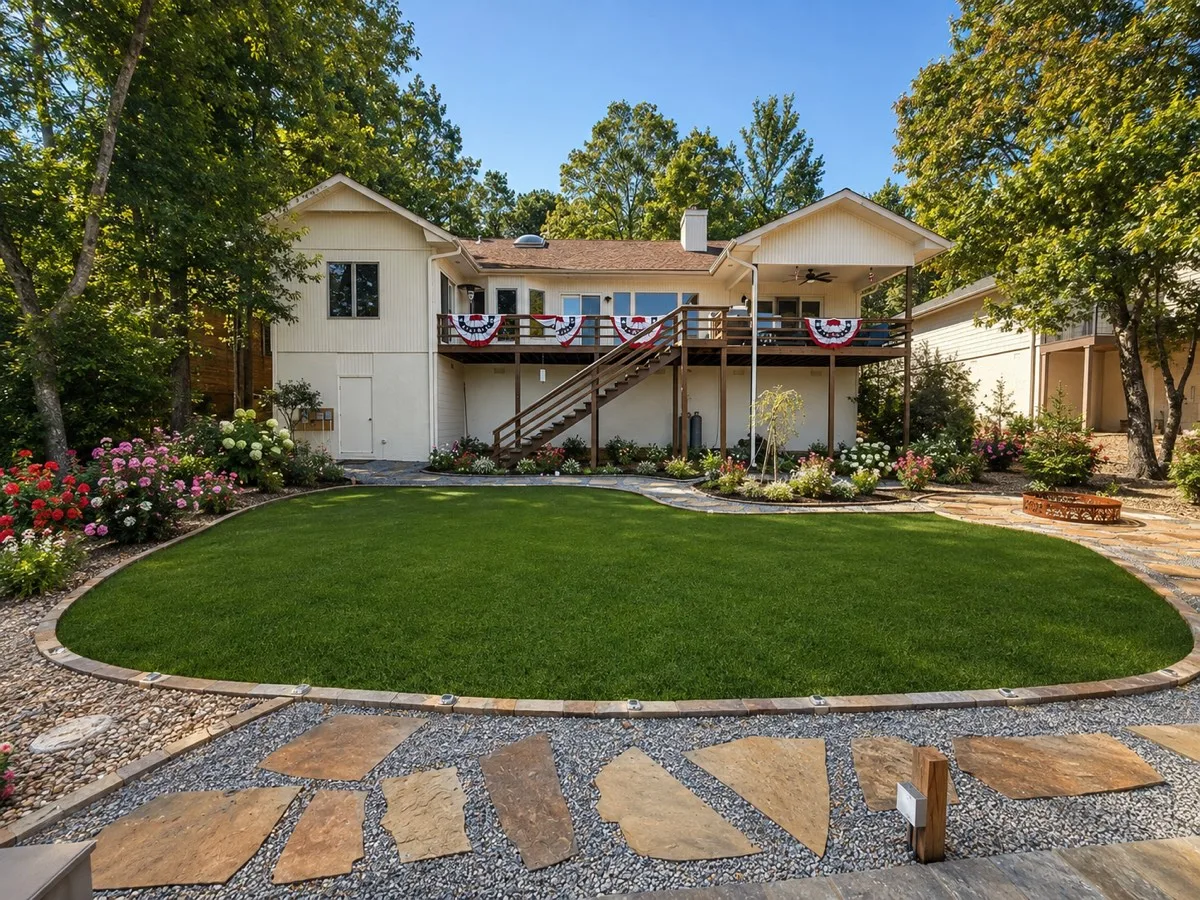 Same angle after — manicured lawn, native stone, flagstone paths and a finished landscape